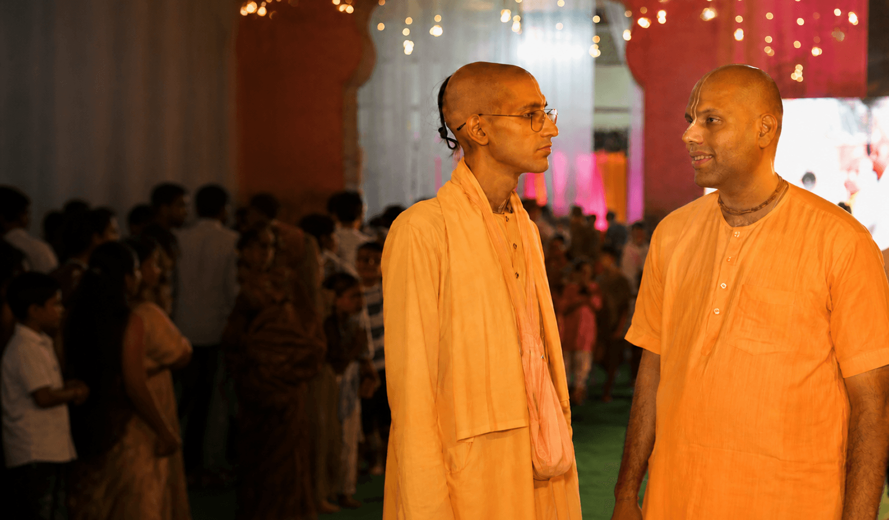 Two sadhus in saffron robes in conversation at a temple festival