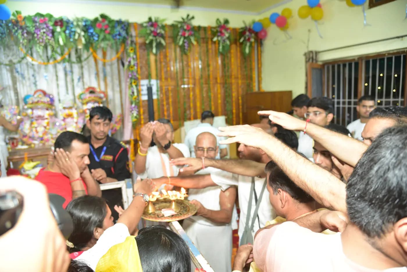 Devotees reaching towards the aarti lamp as the thali is carried through the crowd