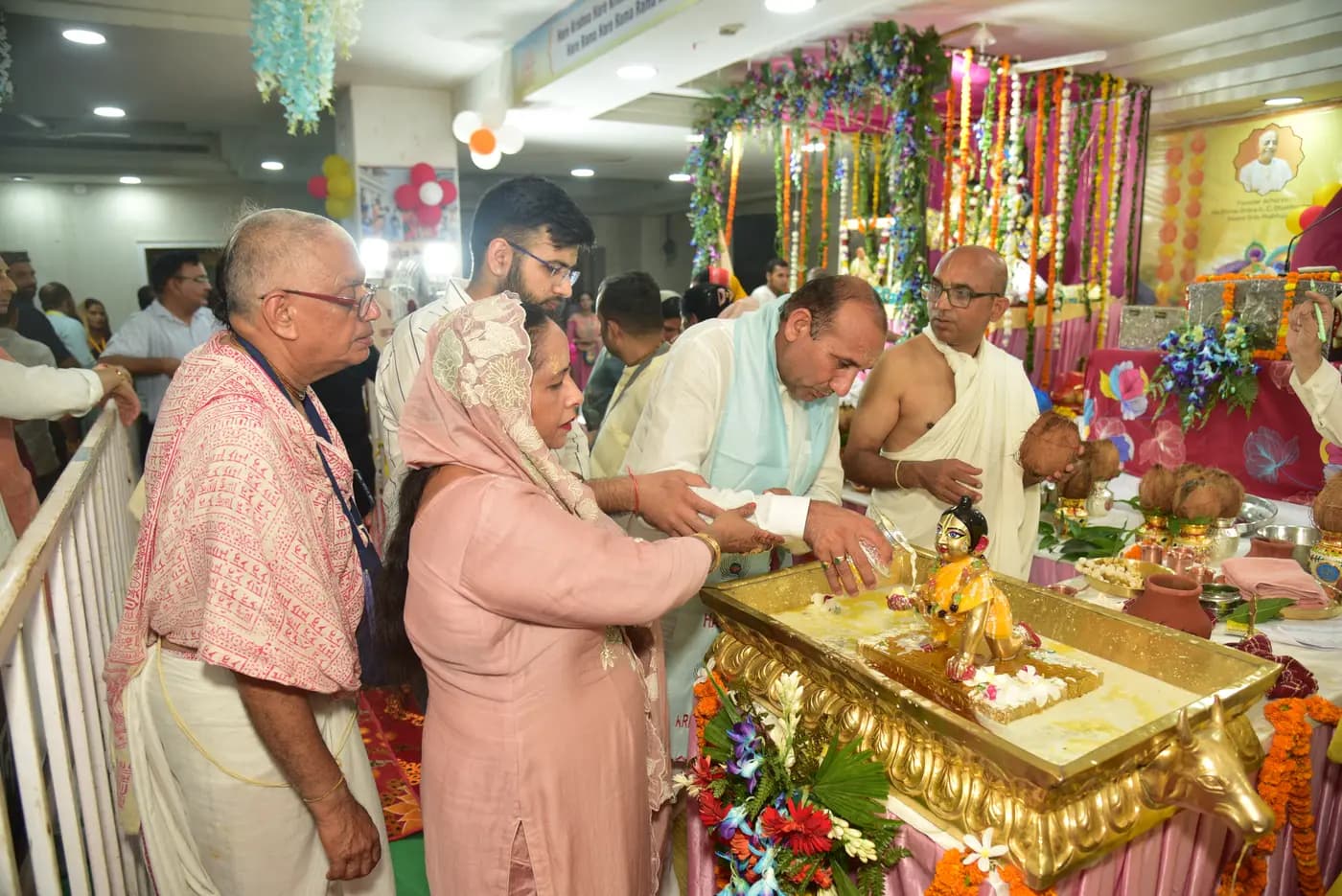 Devotees performing abhishek of the child Krishna deity